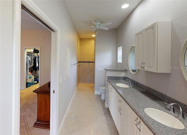 bathroom featuring ceiling fan, tile patterned floors, tiled shower, toilet, and vanity