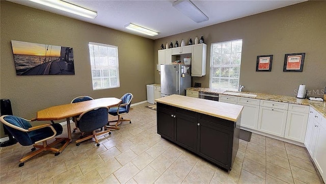 kitchen featuring white cabinets, stainless steel appliances, light stone countertops, and sink