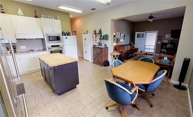 kitchen with premium range hood, white cabinets, stainless steel appliances, and a kitchen island