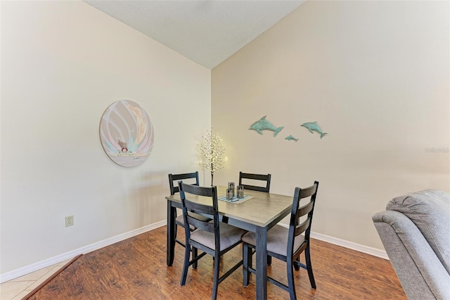 dining room with dark hardwood / wood-style floors and lofted ceiling