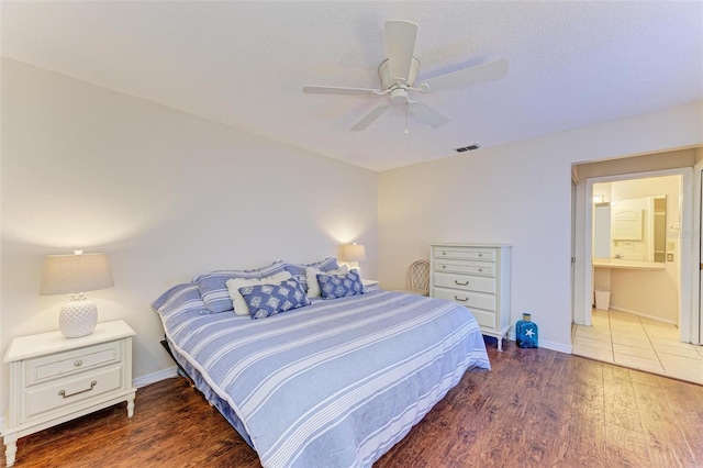 bedroom featuring dark hardwood / wood-style floors, ceiling fan, a textured ceiling, and ensuite bath