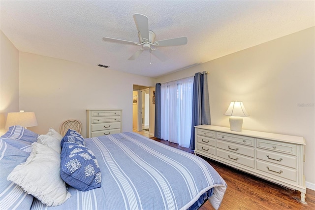 bedroom with a textured ceiling, dark hardwood / wood-style flooring, and ceiling fan