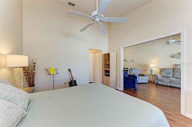 bedroom with a towering ceiling, hardwood / wood-style flooring, and ceiling fan