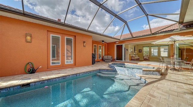 view of pool with glass enclosure, ceiling fan, french doors, a patio area, and an in ground hot tub