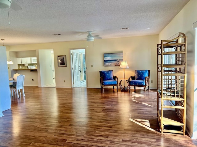 sitting room with a textured ceiling, ceiling fan, and dark wood-type flooring