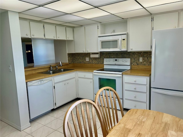 kitchen with white appliances, white cabinets, sink, tasteful backsplash, and light tile patterned flooring