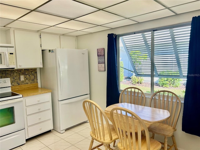 kitchen with a paneled ceiling, white appliances, white cabinets, decorative backsplash, and light tile patterned floors