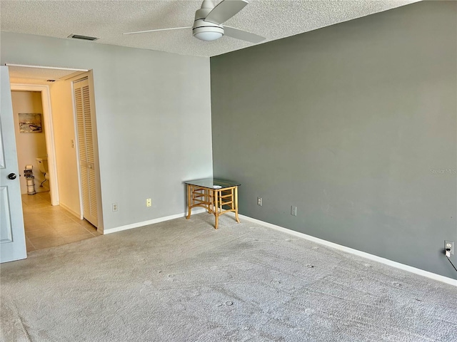 carpeted spare room featuring a textured ceiling and ceiling fan