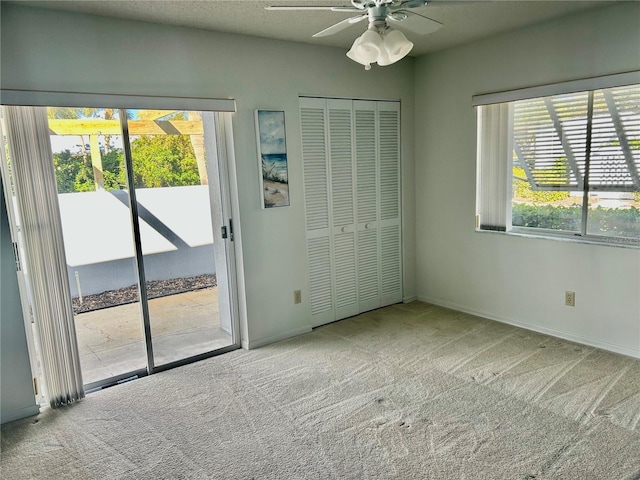 unfurnished bedroom featuring ceiling fan, a closet, access to outside, and multiple windows