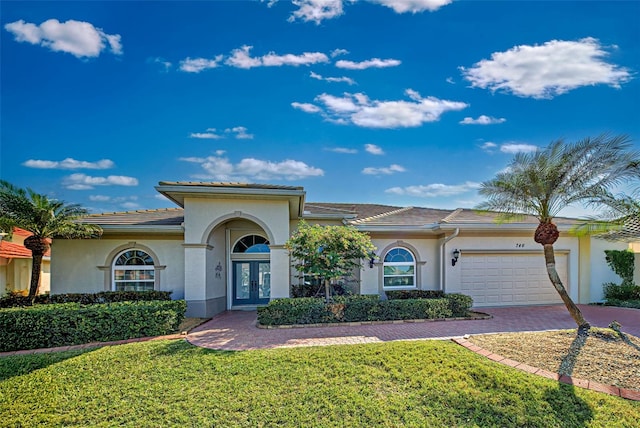 mediterranean / spanish house featuring french doors, a front yard, and a garage