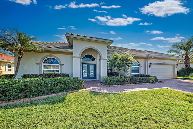 mediterranean / spanish-style home with a front yard, french doors, and a garage