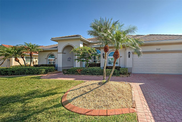 mediterranean / spanish-style home with a garage and a front lawn