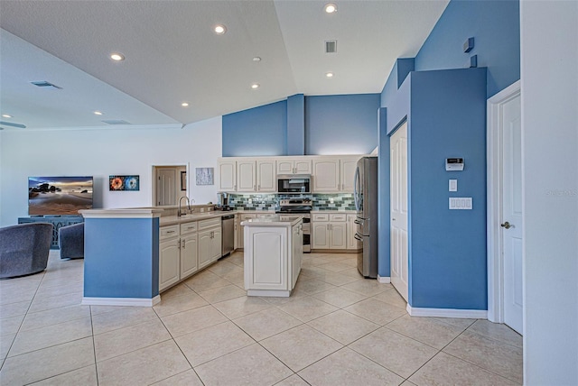 kitchen featuring stainless steel appliances, decorative backsplash, high vaulted ceiling, and a center island with sink