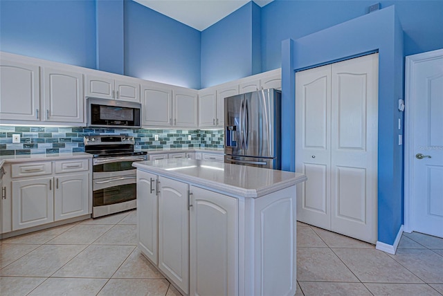 kitchen with white cabinetry, light tile patterned floors, decorative backsplash, a kitchen island, and appliances with stainless steel finishes