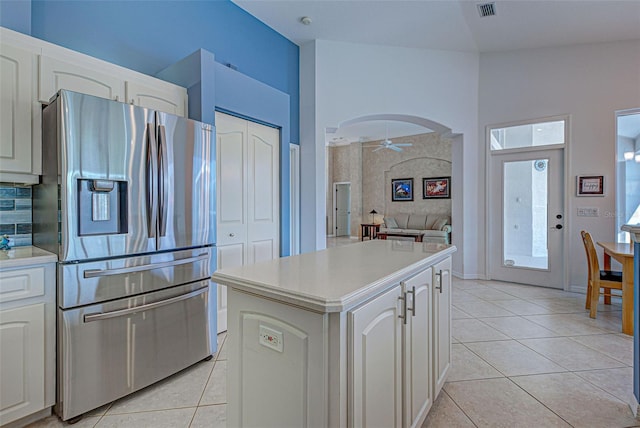 kitchen with light tile patterned floors, ceiling fan, a kitchen island, stainless steel refrigerator with ice dispenser, and white cabinets