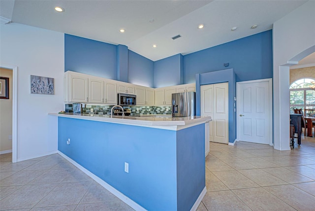 kitchen featuring kitchen peninsula, stainless steel appliances, decorative backsplash, high vaulted ceiling, and light tile patterned flooring