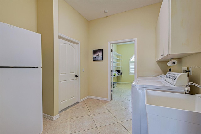 laundry area featuring sink, washer and clothes dryer, light tile patterned floors, and cabinets