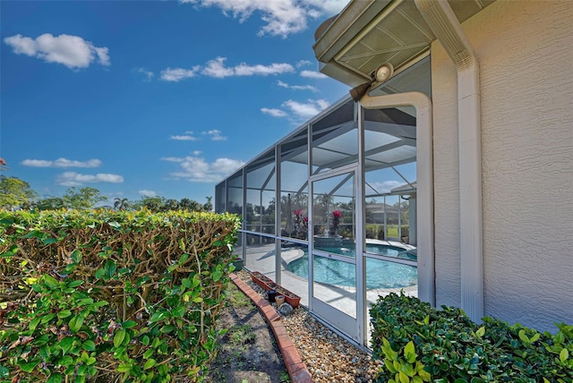 view of swimming pool featuring glass enclosure and a patio