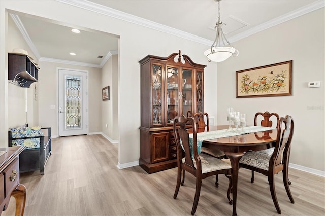 dining space with crown molding and light hardwood / wood-style floors