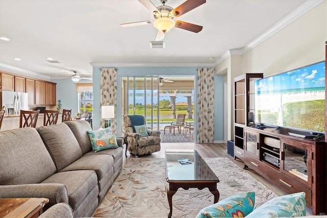 living room featuring a healthy amount of sunlight, light hardwood / wood-style floors, and ornamental molding