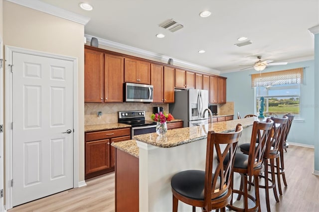 kitchen with a kitchen breakfast bar, light hardwood / wood-style flooring, ornamental molding, and appliances with stainless steel finishes