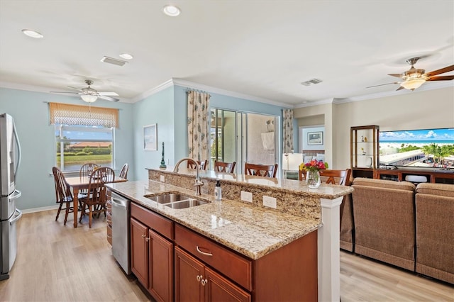 kitchen featuring sink, stainless steel appliances, crown molding, a kitchen island with sink, and light wood-type flooring