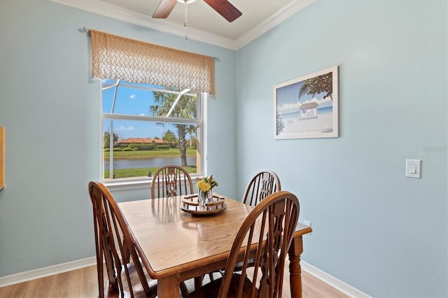 dining space with light hardwood / wood-style floors, a wealth of natural light, ornamental molding, and a water view