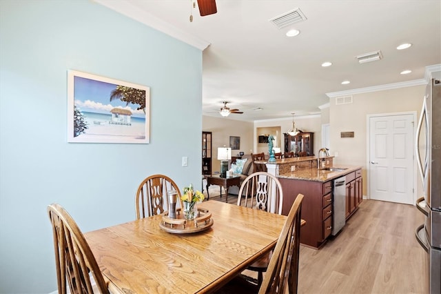 dining space featuring light hardwood / wood-style flooring, ceiling fan, crown molding, and sink