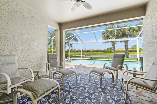 sunroom featuring ceiling fan, a pool, and a water view