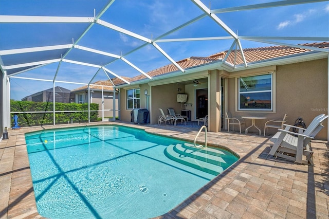 view of pool with ceiling fan, a lanai, and a patio