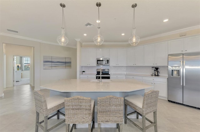 kitchen featuring white cabinetry, an island with sink, stainless steel appliances, and ornamental molding