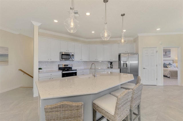 kitchen with white cabinets, appliances with stainless steel finishes, a kitchen island with sink, and sink