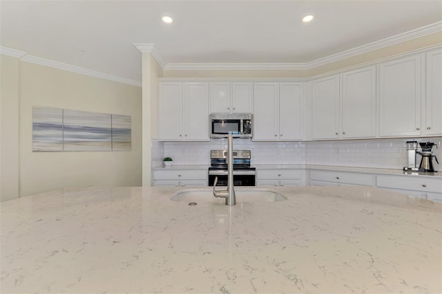 kitchen with light stone countertops, white cabinetry, ornamental molding, and appliances with stainless steel finishes