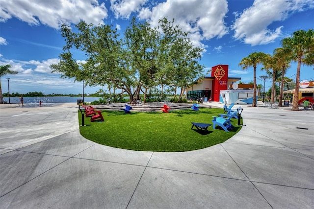 surrounding community with a water view and a lawn