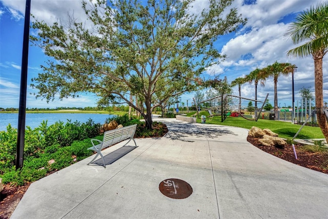 view of property's community featuring a water view, a patio area, and a lawn