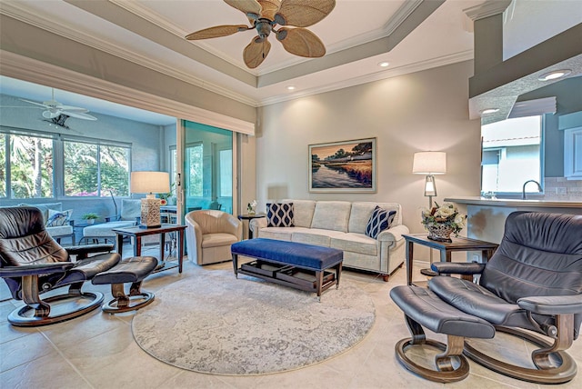 tiled living room with a tray ceiling, ceiling fan, crown molding, and sink