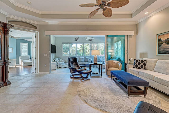 living room with light tile patterned floors, ornamental molding, and a tray ceiling