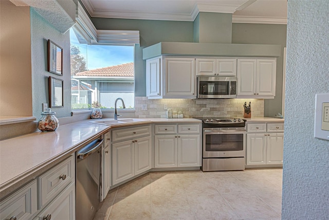 kitchen featuring backsplash, stainless steel appliances, crown molding, sink, and white cabinetry