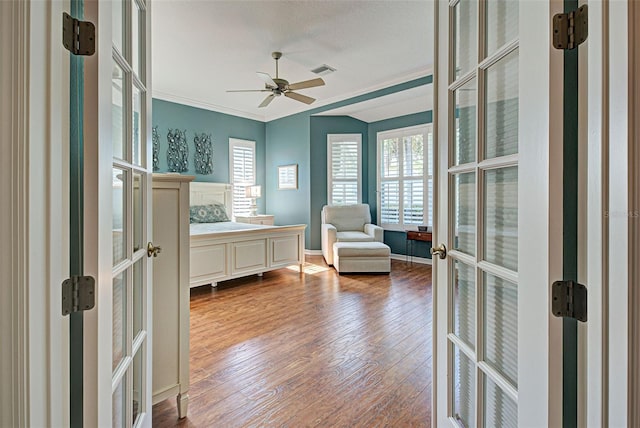 bedroom featuring hardwood / wood-style flooring, ceiling fan, crown molding, and french doors