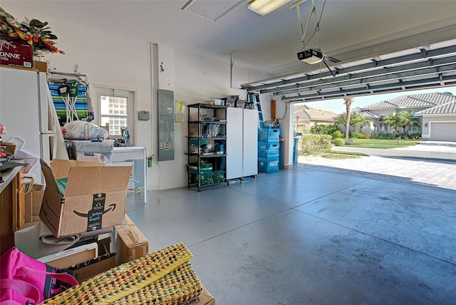 garage featuring white refrigerator, electric panel, and a garage door opener