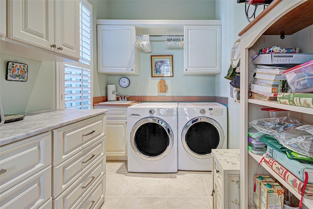 laundry area with washing machine and clothes dryer, a wealth of natural light, light tile patterned floors, and cabinets