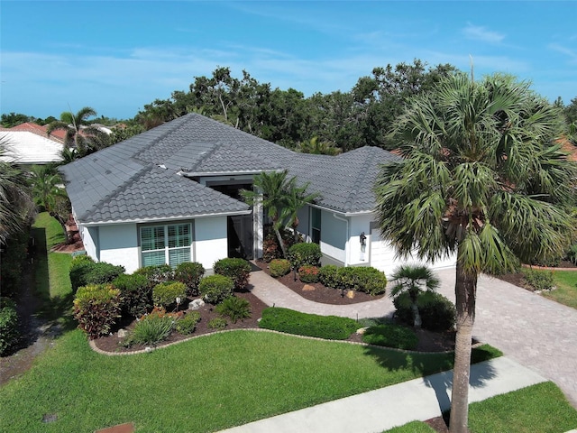 single story home featuring a tile roof, a front yard, and stucco siding