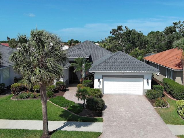 view of front of house with a tile roof, driveway, a garage, a front yard, and stucco siding