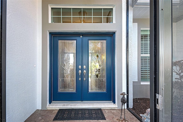 property entrance featuring stucco siding and french doors