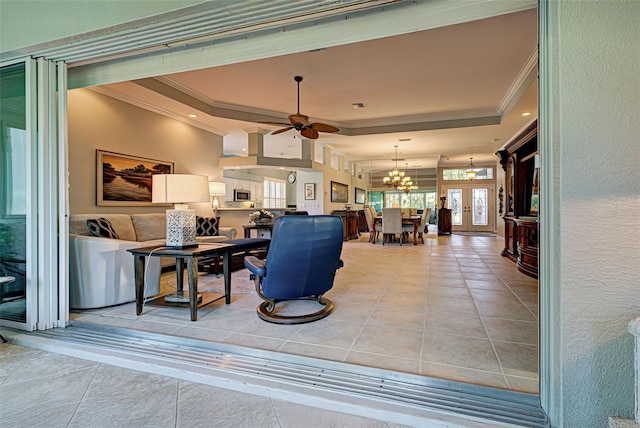 tiled living room featuring a tray ceiling, ornamental molding, and ceiling fan with notable chandelier