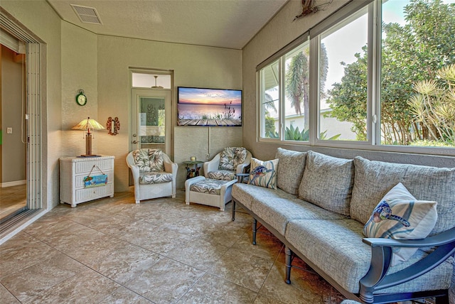 living room featuring a textured wall, a textured ceiling, and visible vents