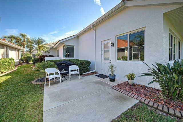 exterior space featuring a patio area, a lawn, and stucco siding