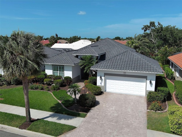 single story home with stucco siding, an attached garage, driveway, and a tile roof