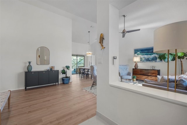 living room featuring ceiling fan with notable chandelier, wood-type flooring, and high vaulted ceiling