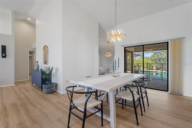 dining area featuring light hardwood / wood-style floors, a high ceiling, and an inviting chandelier